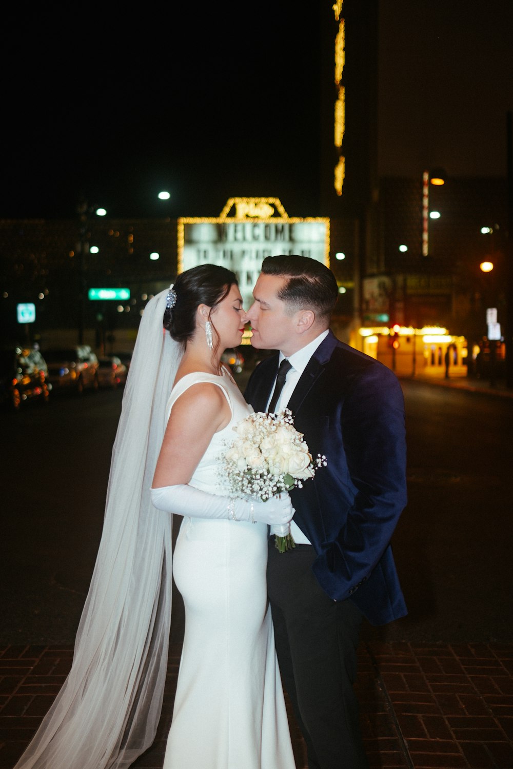 a bride and groom kissing in front of the welcome sign