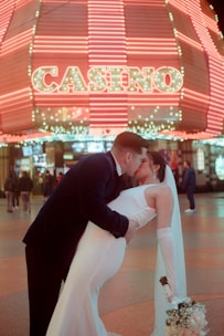 a bride and groom kissing in front of a casino