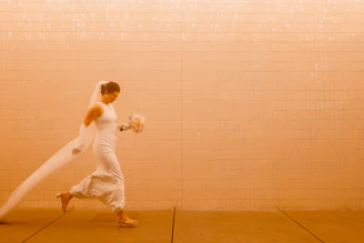 A dramatic black and white portrait of a bride holding a bouquet against a textured wall.