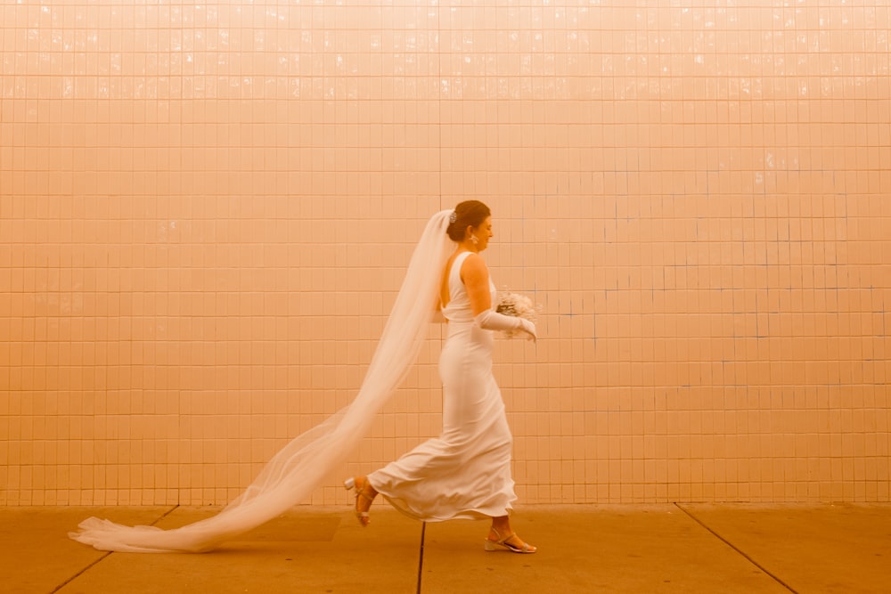 a woman in a white dress and veil walking