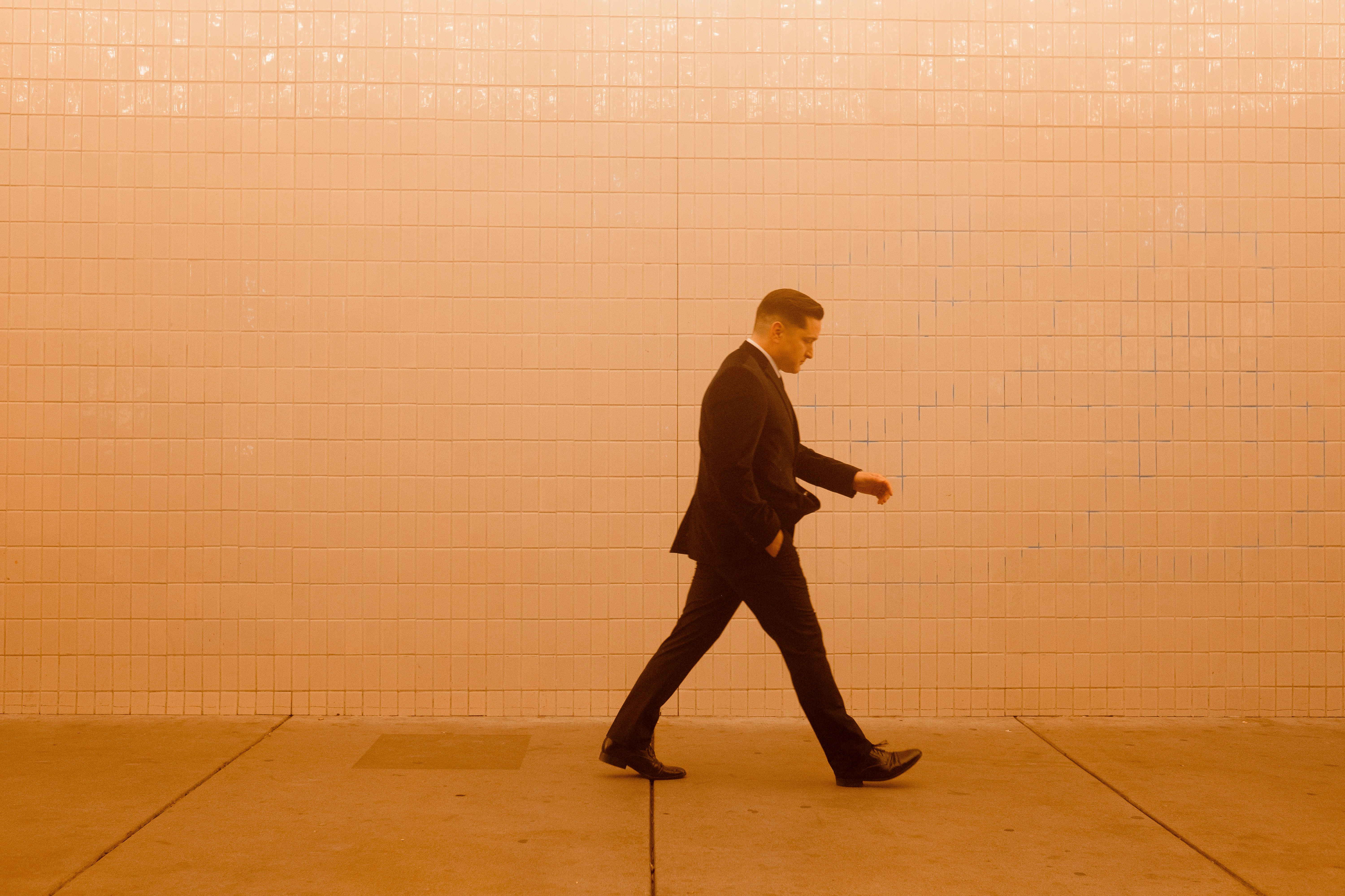 a man in a suit walking down a sidewalk (Photo by Wesley Tingey on Unsplash)