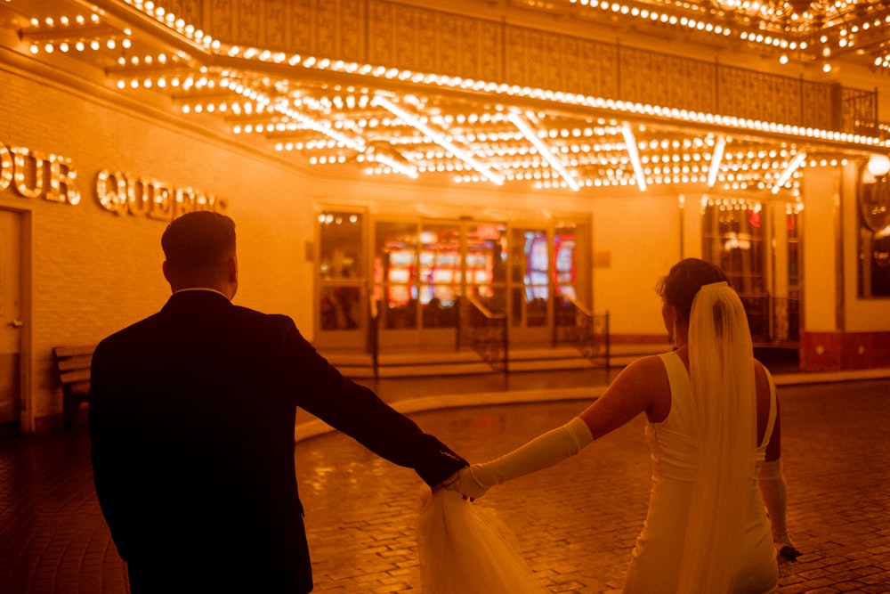 a bride and groom holding hands in front of a building