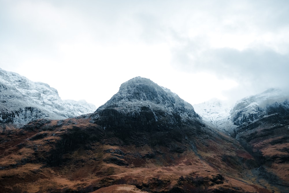 a mountain range covered in snow on a cloudy day