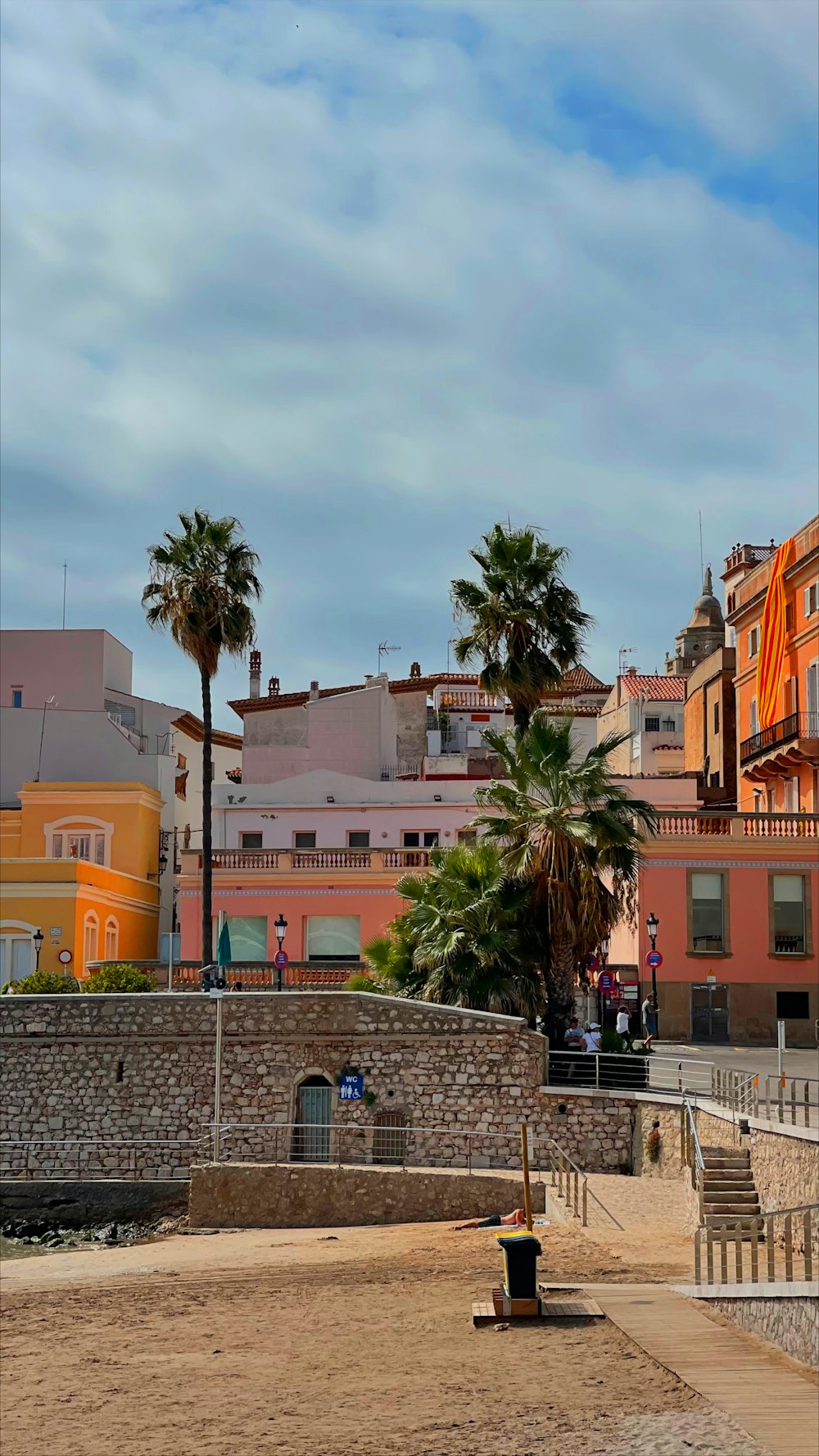 a beach area with palm trees and buildings in the background