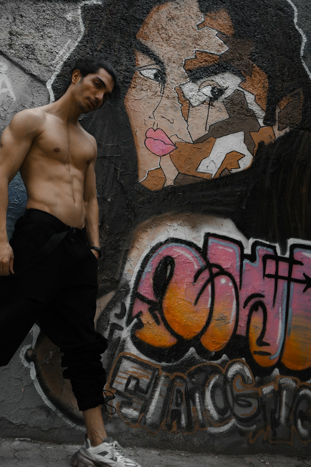 a man standing in front of a wall with graffiti