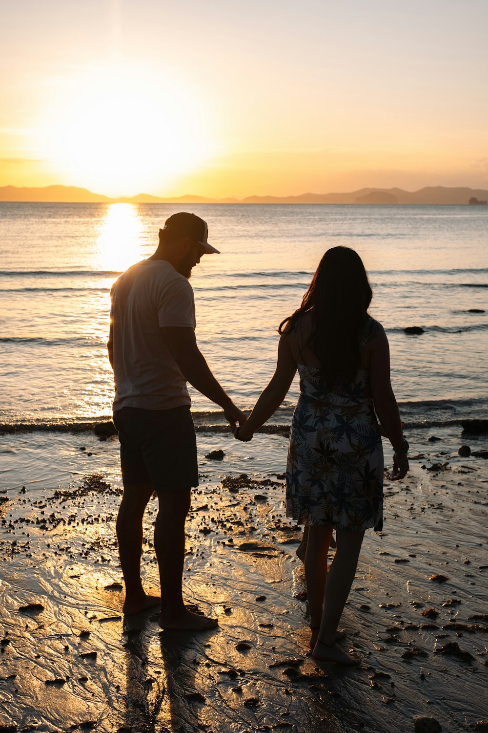 a man and a woman holding hands on the beach