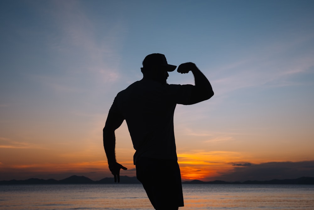 a silhouette of a man standing on a beach at sunset