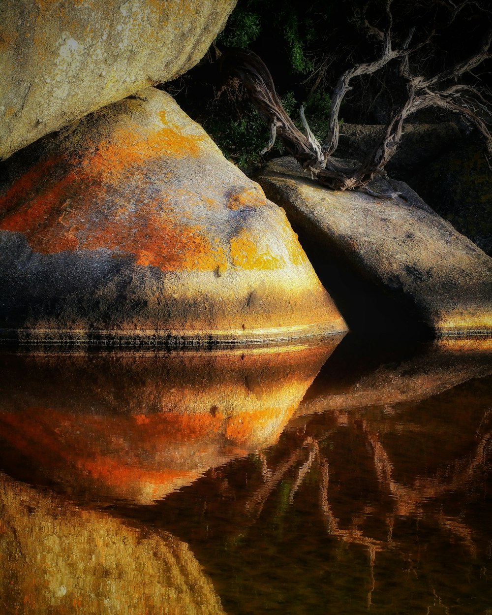 a large rock sitting next to a body of water