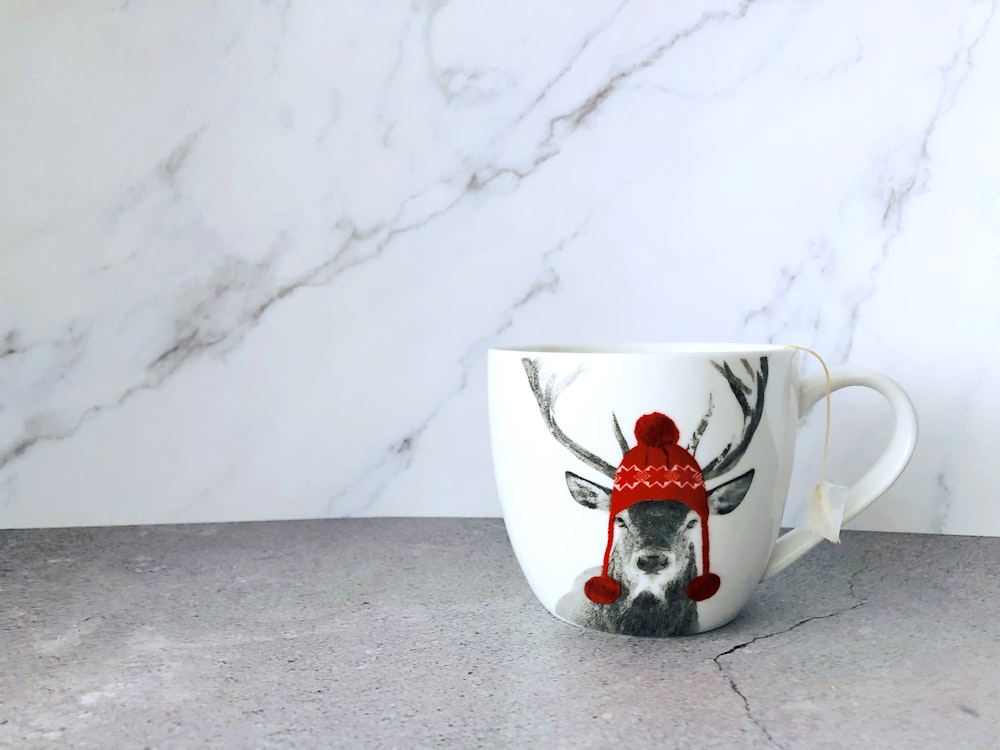 a coffee cup with a reindeer wearing a red hat