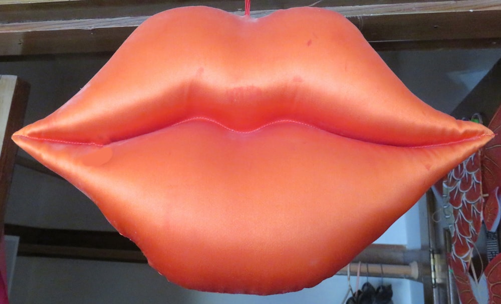a large orange lip shaped balloon hanging from a ceiling