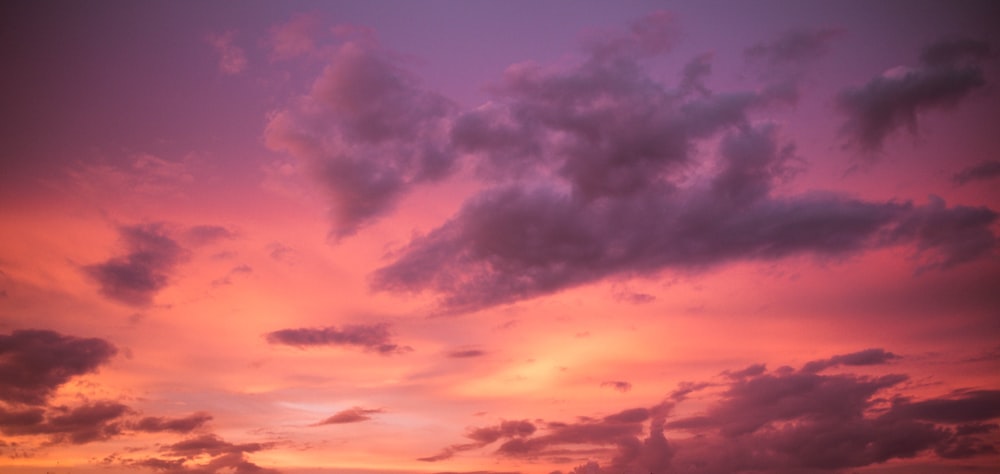 a sunset with clouds in the sky and a boat in the water