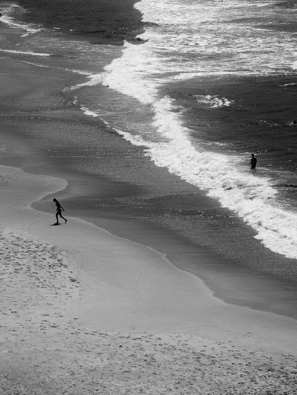 a couple of people walking along a beach next to the ocean