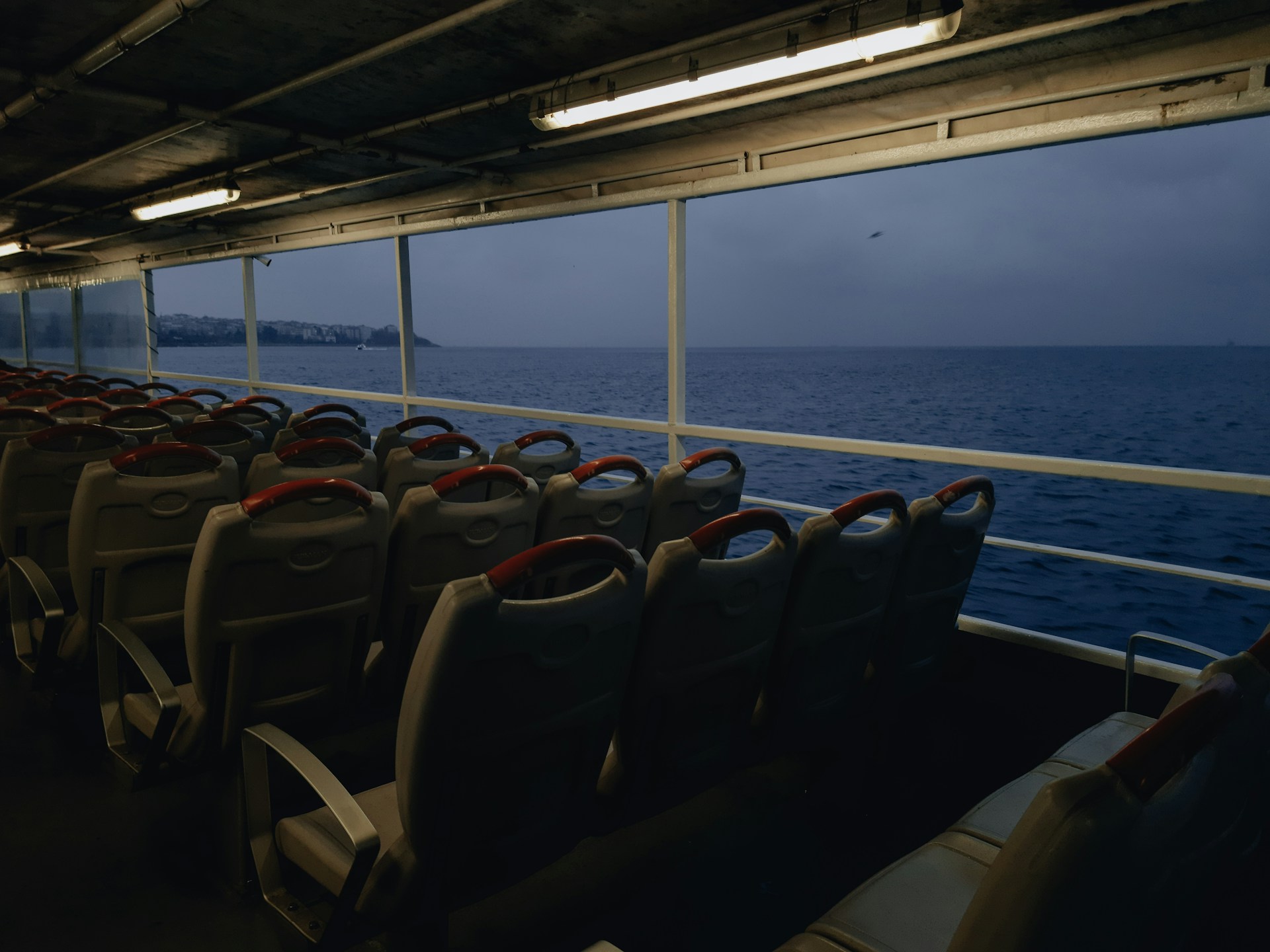 The spacious and inviting interior of the Tooth Ferry catamaran, showcasing cozy seating, polished wood finishes, and large windows framing the sea.