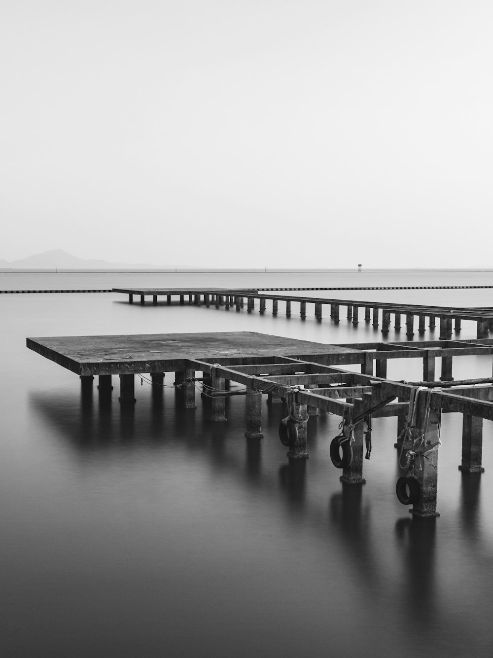 a black and white photo of a pier in the water