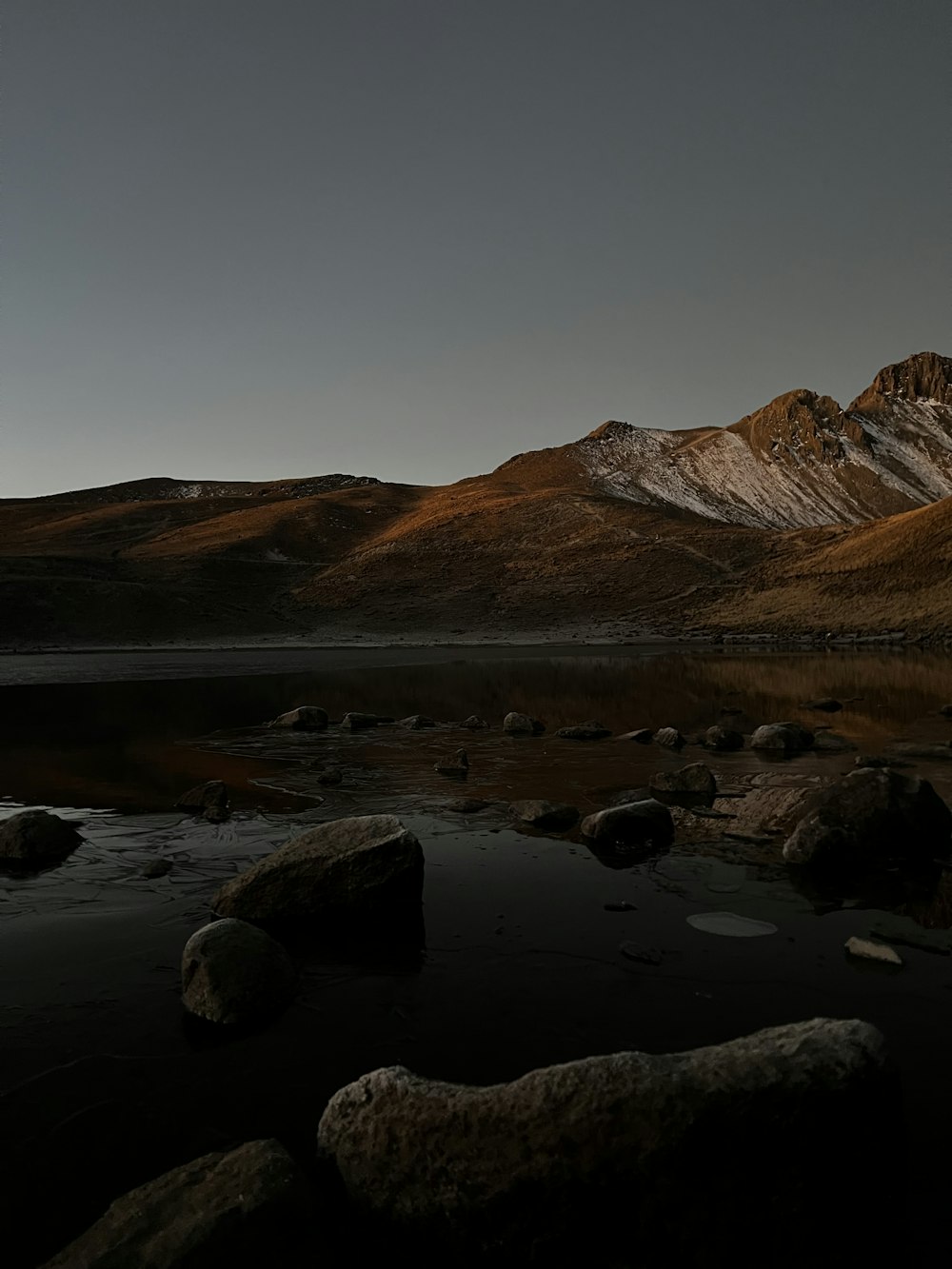 a mountain range with a body of water in the foreground