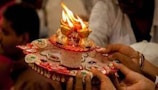 Close-up of hands distributing food plates with religious decorations in the background.