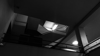 A stark black-and-white photograph of a sleek, minimalist architectural interior featuring sharp lines and expansive empty space.