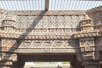 Intricate stone carvings depicting geometric and floral patterns cover the surface of an ancient architectural structure. The design features highly detailed lattice work and symmetrical motifs, characteristic of traditional craftsmanship.