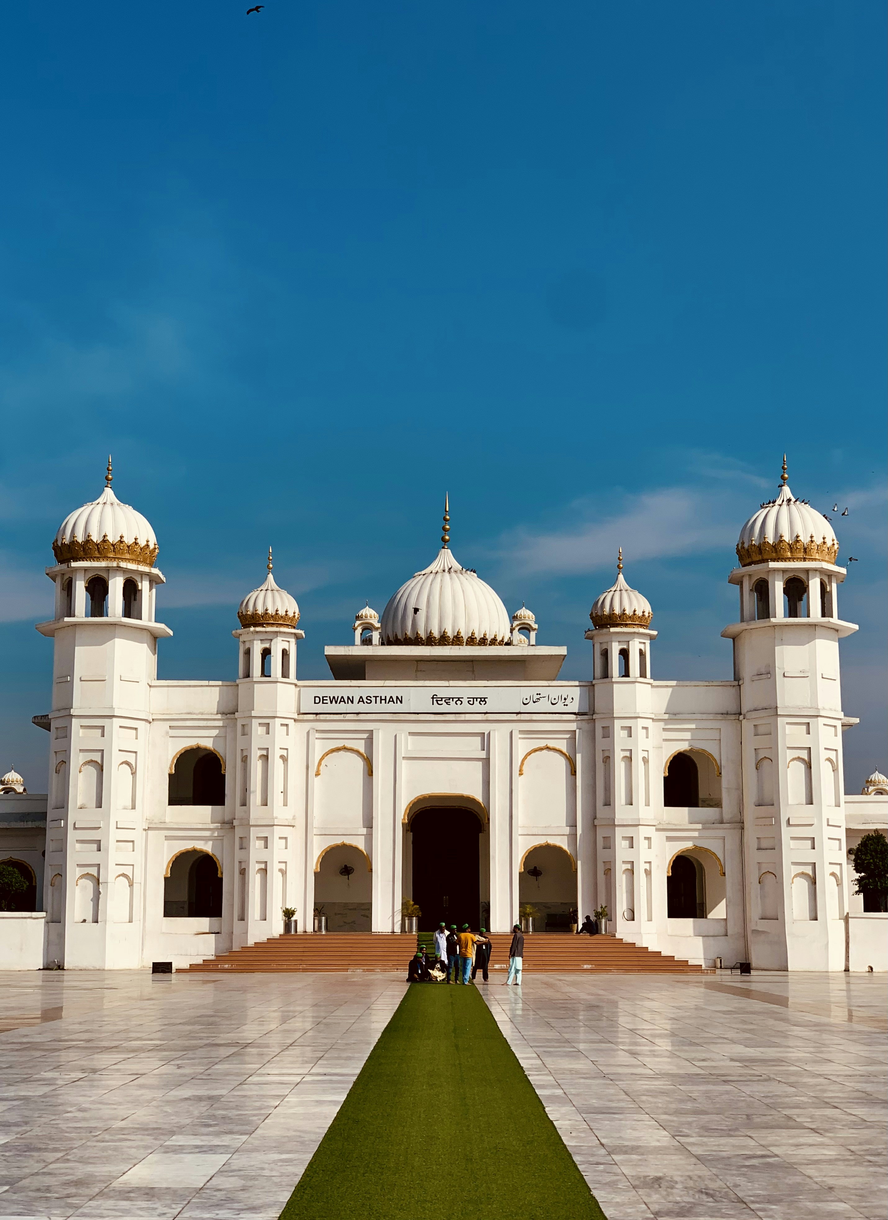 a large white building with a green lawn in front of it