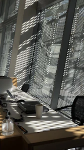 Photo of a cheerful cleaning professional carefully polishing a modern office desk, sunlight streaming through a nearby window.