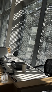 A professional cleaner carefully wiping a modern office desk with natural light streaming in.