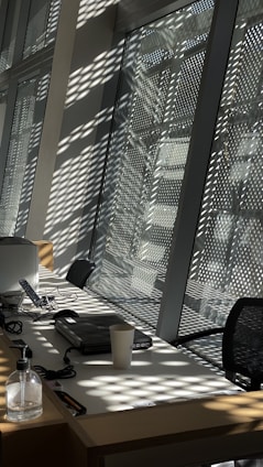A friendly cleaner in uniform carefully wiping down a bright office desk with sunlight streaming through the window.
