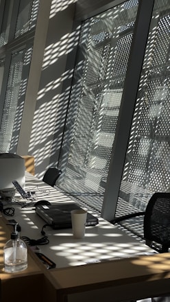 A professional cleaner wiping down an office desk with natural light streaming through the window.