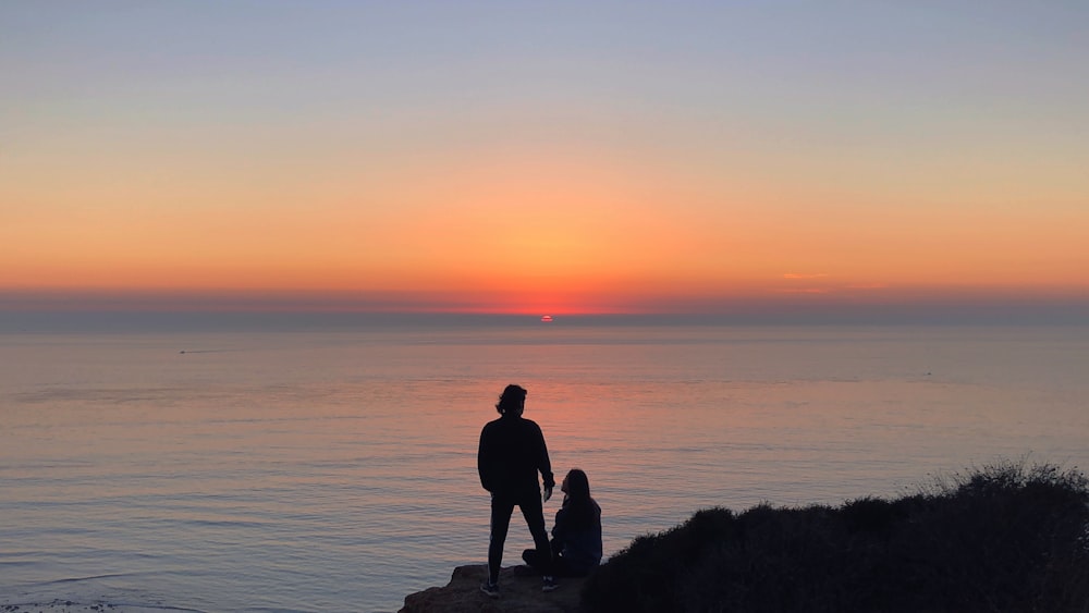 a couple of people standing on top of a cliff