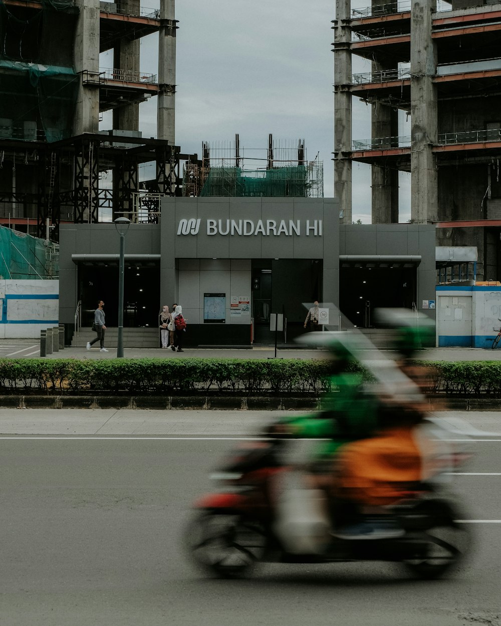 a man riding a motorcycle down a street next to a tall building