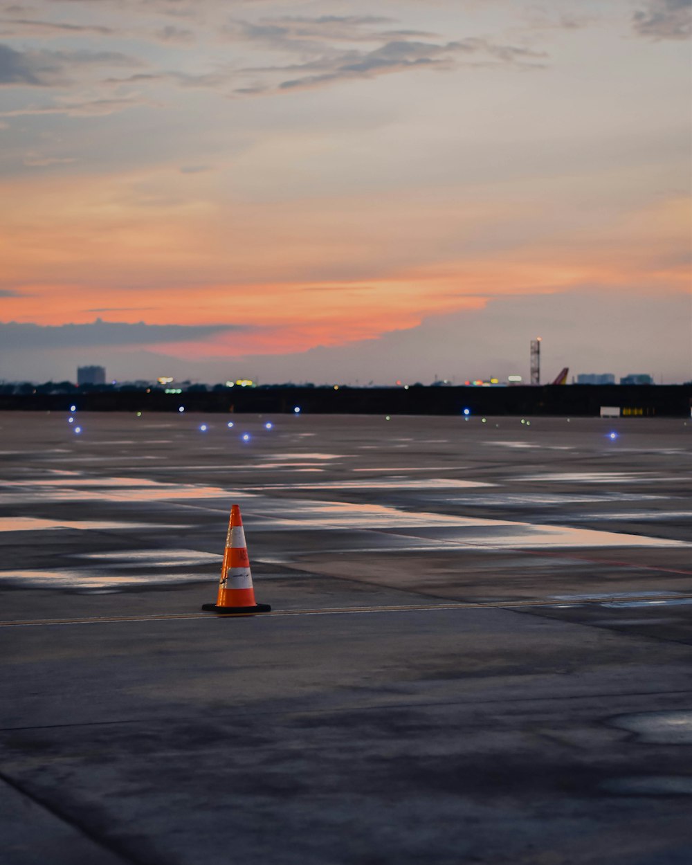 an airport tarmac with an orange cone in the foreground