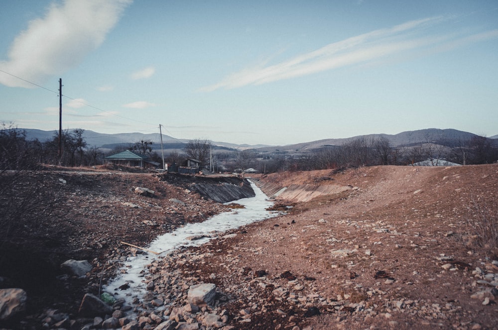 a stream of water running through a dirt field