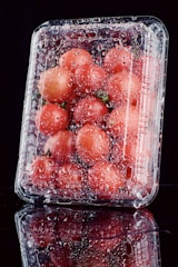 a plastic container filled with lots of tomatoes