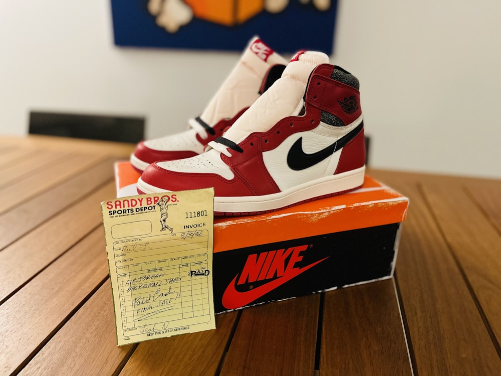 a pair of red and white sneakers sitting on top of a box