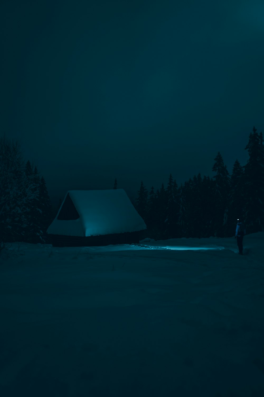 a man standing in the snow next to a tent
