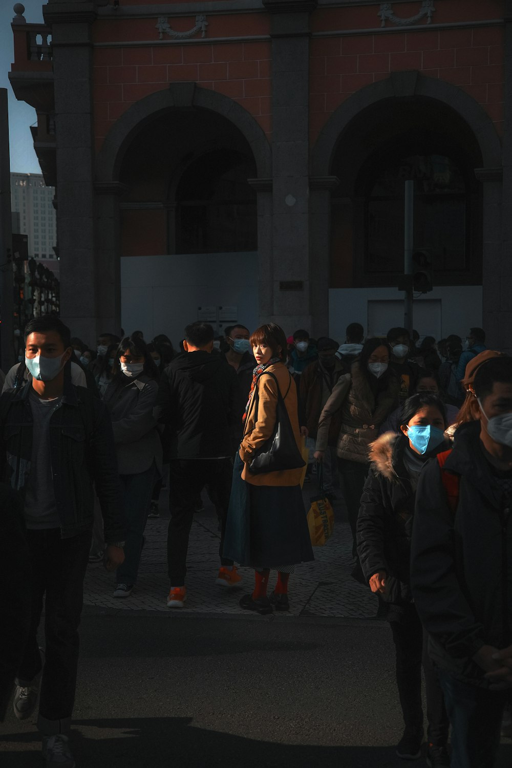 a group of people walking down a street wearing face masks