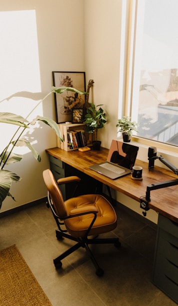 a desk with a laptop and a potted plant