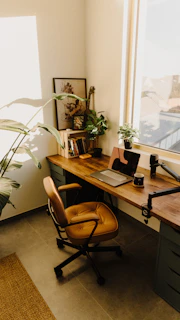 a desk with a laptop and a potted plant