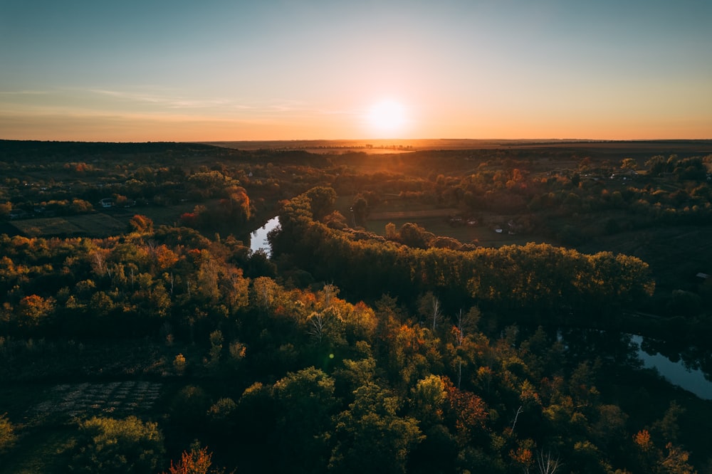 the sun is setting over a river in a wooded area