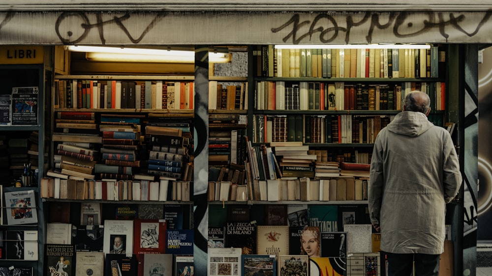 Un uomo in piedi davanti a una libreria piena di libri