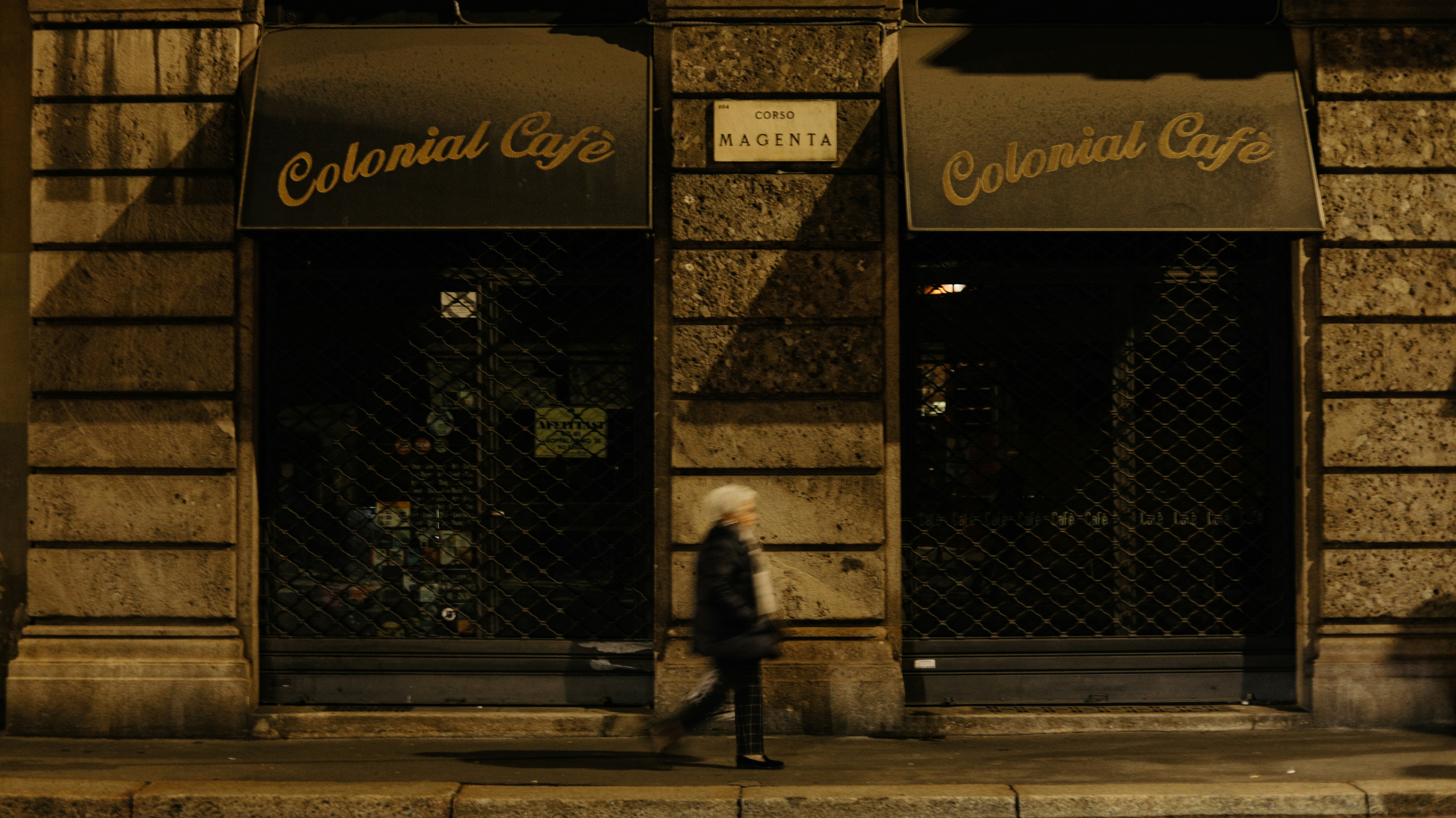 Una donna che cammina lungo un marciapiede accanto a un edificio alto