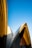 Architectural design with curved, overlapping structures set against a clear, blue sky. The building features a combination of smooth and textured surfaces, with distinct shadows cast by the sun.