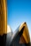 Architectural design with curved, overlapping structures set against a clear, blue sky. The building features a combination of smooth and textured surfaces, with distinct shadows cast by the sun.