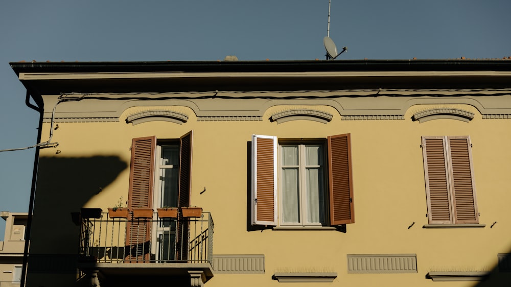 a yellow building with shutters and a balcony
