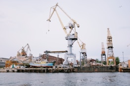 A modern shipyard with cranes and green energy installations under a clear blue sky.
