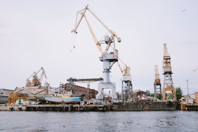 A modern shipyard with cranes and green energy installations under a clear blue sky.
