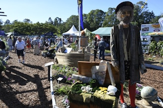 A lively garden fair with stands showcasing plants, tools, and homemade compost demonstrations.