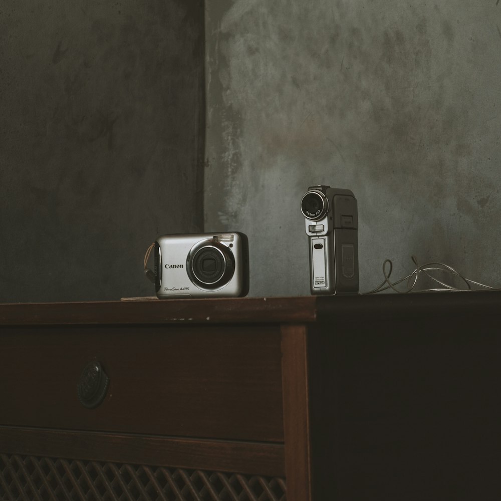 um par de câmeras sentadas em cima de uma mesa de madeira