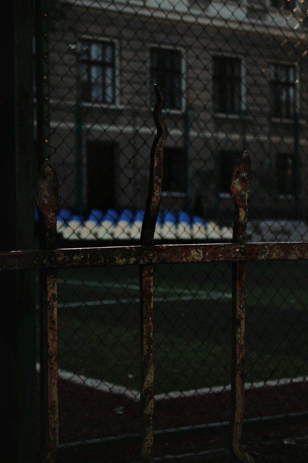 a rusted iron fence with a building in the background