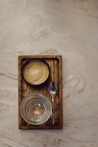 A sleek metal tray with a brushed finish resting on a wooden table.