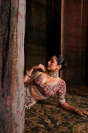 A close-up of a woman wearing a richly embroidered Zard kaftan in warm beige tones, softly lit against a vintage backdrop.